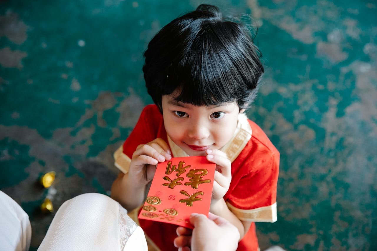 An Adult Giving a Red Envelope to a Young Boy